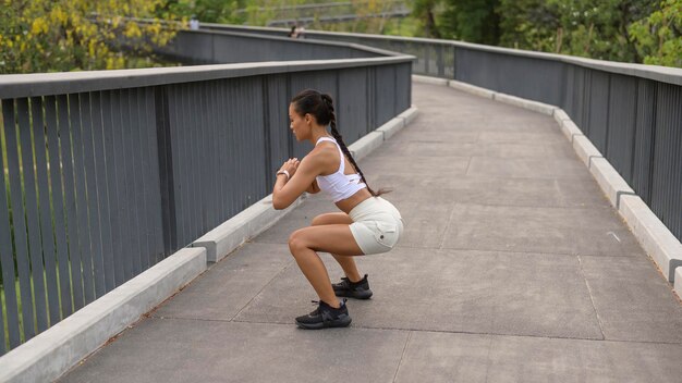 Una joven mujer fitness en ropa deportiva haciendo ejercicio en el parque de la ciudad Saludable y estilos de vida