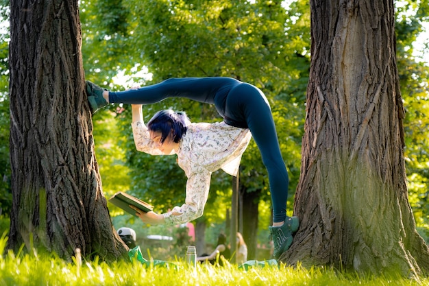 Joven mujer flexible leyó el libro de picnic. Concepto de individualidad, creatividad y destaque.