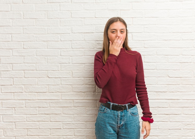 Joven mujer fría sobre una pared de ladrillos cansada y con mucho sueño