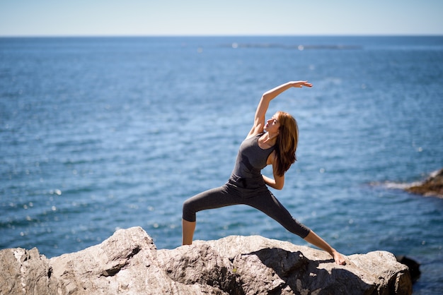 Joven mujer haciendo yoga en la playa