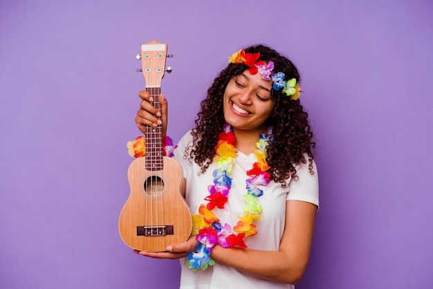 Joven mujer hawaiana jugando ukelele aislado en pared púrpura