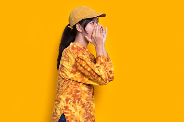 joven mujer hermosa asiática gritando y gritando anunciando aislado sobre fondo amarillo