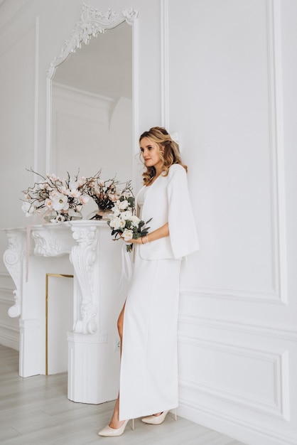 joven mujer hermosa novia con un vestido de novia con un ramo de flores en un interior luminoso