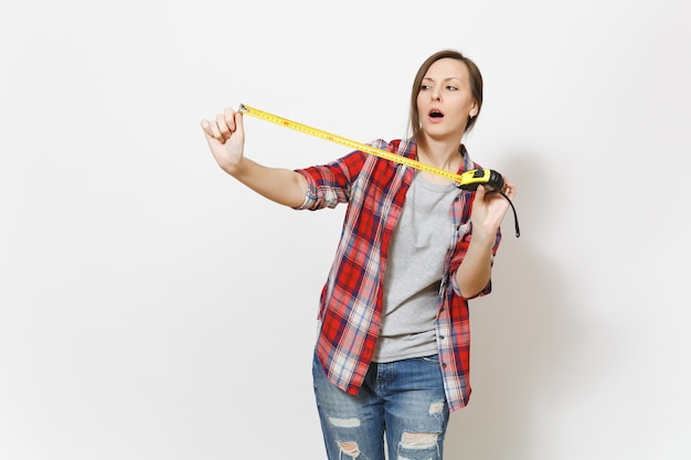 Joven mujer hermosa preocupada en ropa casual con cinta métrica aislada sobre fondo blanco. Instrumentos, accesorios para habitación de apartamento de renovación. Reparar el concepto de hogar. Área de publicidad.