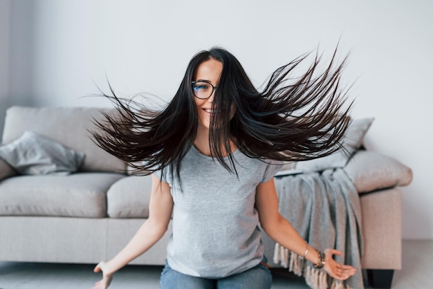 Joven mujer hermosa con ropa informal y anteojos se divierte sola en casa.