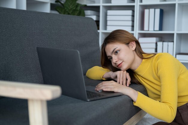 Joven mujer hermosa teniendo un tiempo de relajación mientras usa una computadora portátil y sentada en el suelo de la sala de estar
