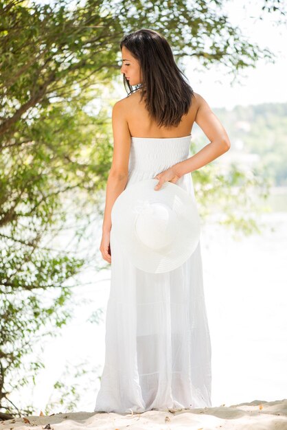 Foto joven mujer hermosa con vestido blanco relajándose en la naturaleza.