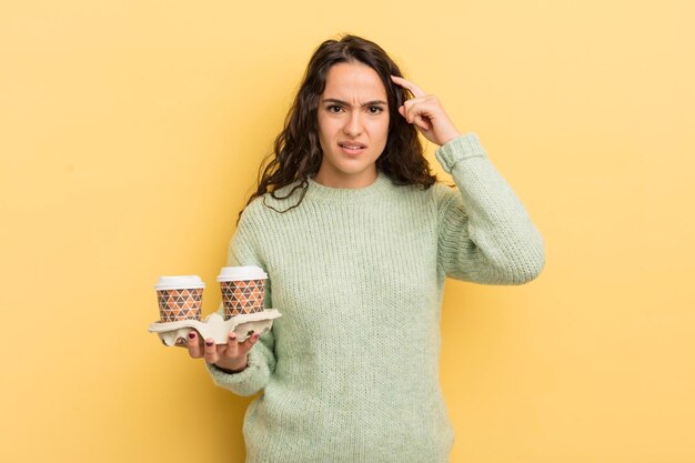 Joven mujer hispana bonita que se siente confundida y perpleja mostrando que estás loco por el concepto de café para llevar