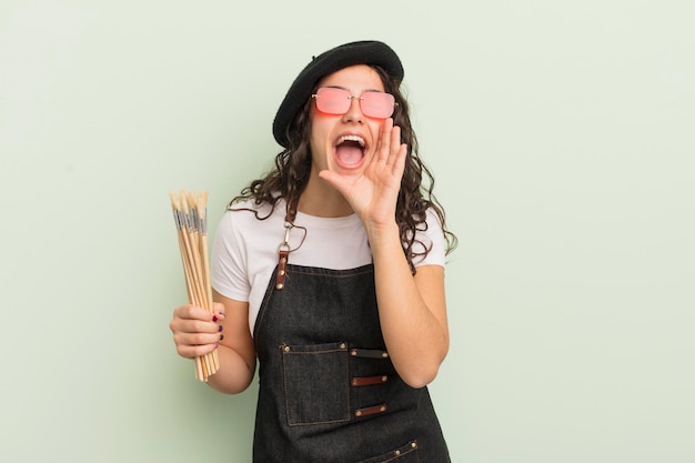 Joven mujer hispana bonita que se siente feliz, dando un gran grito con las manos al lado de la boca. concepto de artista