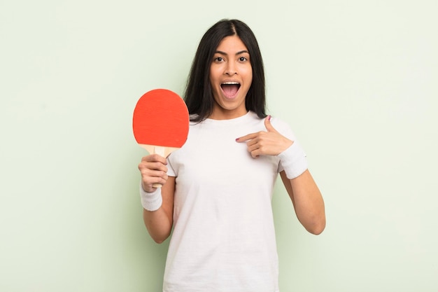 Joven mujer hispana bonita que se siente feliz y se señala a sí misma con un concepto de ping pong emocionado