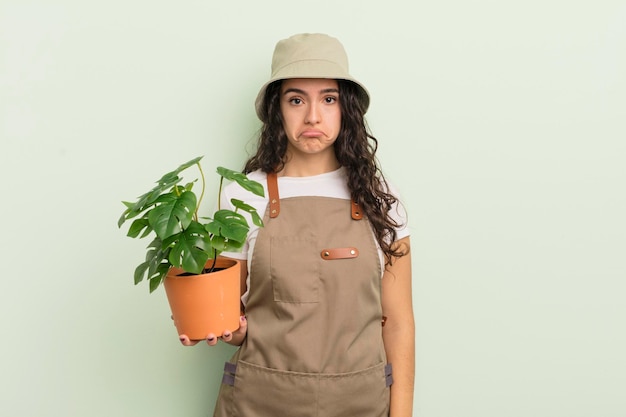 Joven mujer hispana bonita que se siente triste y quejumbrosa con una mirada infeliz y un concepto de granjero o jardinero llorando