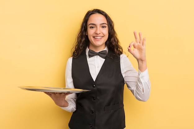 joven mujer hispana bonita sintiéndose sorprendida, riendo y celebrando el éxito. concepto de camarero y bandeja