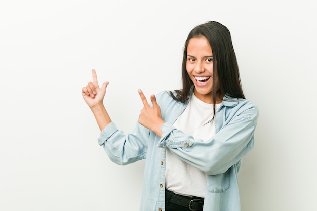 Foto joven mujer hispana señalando con el dedo índice a un espacio de copia, expresando emoción y deseo.