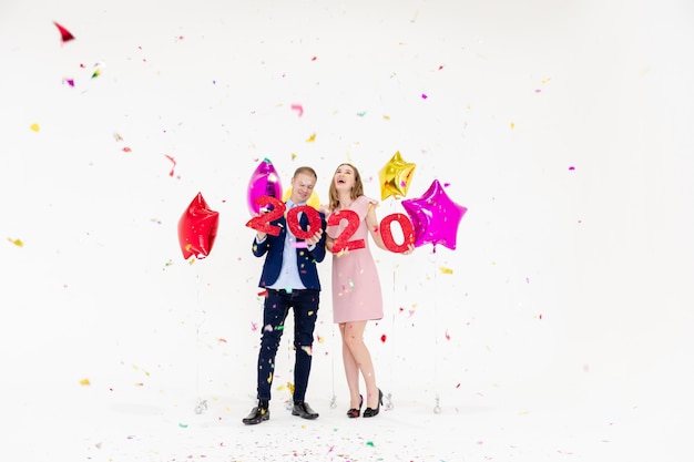 Joven mujer y hombre se divierten con feliz año nuevo 2020