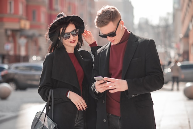 Joven mujer y hombre mirando usando un teléfono