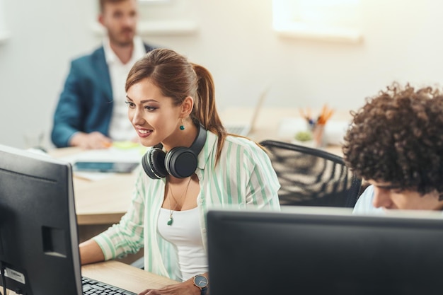 Joven mujer independiente feliz está trabajando en un nuevo proyecto de negocios en la computadora en la oficina informal.