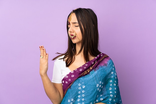 Joven mujer india aislada en la pared púrpura con expresión cansada y enferma