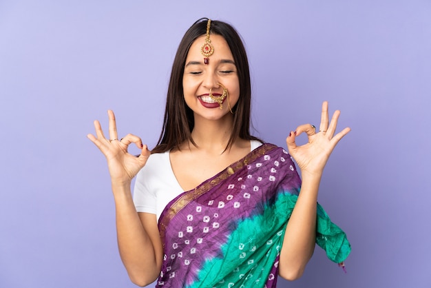 Joven mujer india aislada en la pared púrpura en pose zen