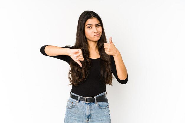 Foto joven mujer india aislada en púrpura mostrando los pulgares hacia arriba y hacia abajo, difícil elegir el concepto