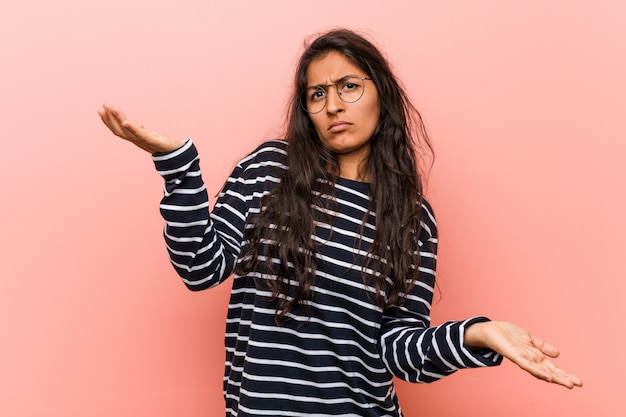 Joven mujer India intelectual dudando entre dos opciones.