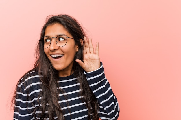 Joven mujer india intelectual tratando de escuchar un chisme.