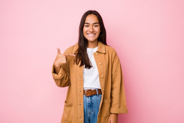 Joven mujer india de raza mixta aislada persona apuntando con la mano a un espacio de copia de camisa, orgulloso y seguro