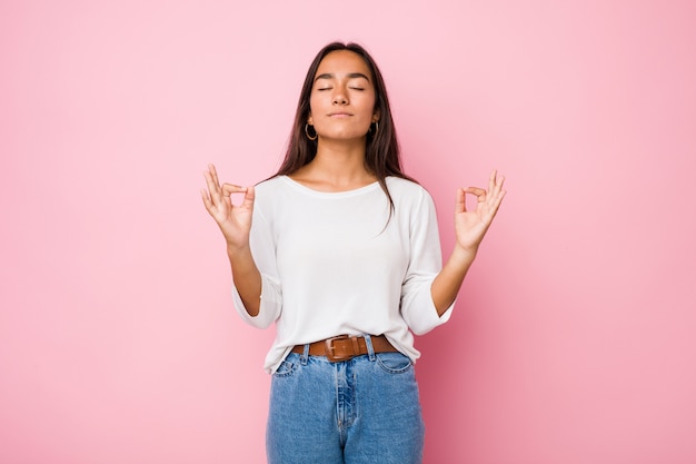 Joven mujer india de raza mixta se relaja después de un duro día de trabajo, ella está realizando yoga.