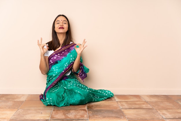 Joven mujer India sentada en el suelo en pose zen