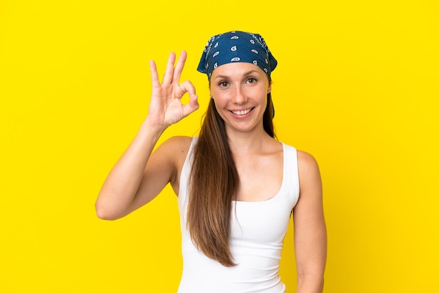 Joven mujer inglesa aislada sobre fondo amarillo mostrando el signo de ok con los dedos