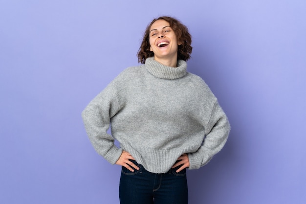 Foto joven mujer inglesa en púrpura posando con los brazos en la cadera y sonriendo