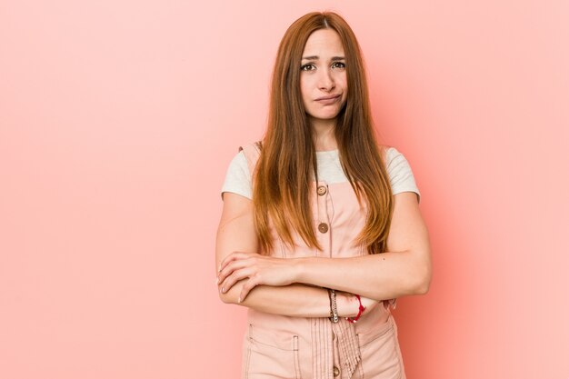 Joven mujer de jengibre con pecas infelices con expresión sarcástica.