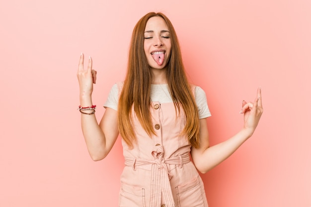 Joven mujer de jengibre con pecas mostrando gesto de rock con los dedos