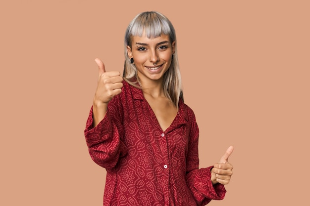 Foto joven mujer joven caucásica en el estudio levantando ambos pulgares sonriendo y confiada