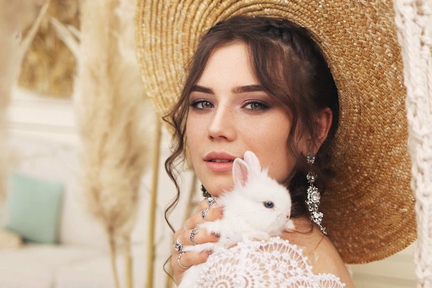 Joven mujer joven con un conejo en sus manos, elegante retrato femenino de moda