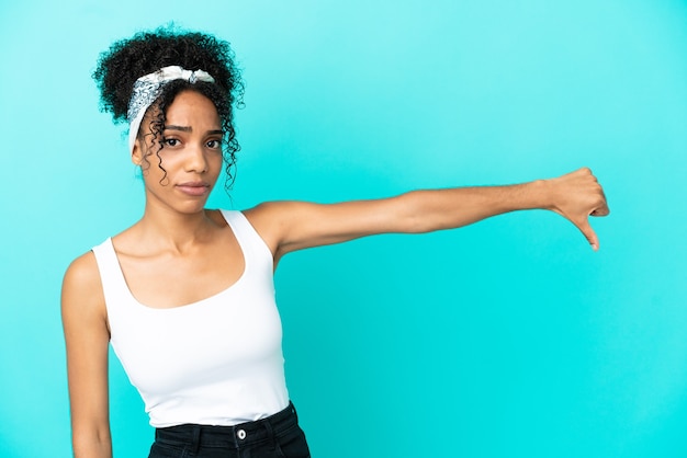 Foto joven mujer latina aislada sobre fondo azul mostrando el pulgar hacia abajo con expresión negativa