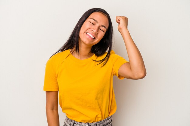 Joven mujer latina aislada sobre fondo blanco celebrando una victoria, pasión y entusiasmo, expresión feliz.