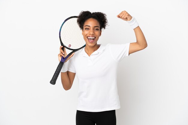 Joven mujer latina aislada sobre fondo blanco jugando al tenis y celebrando una victoria