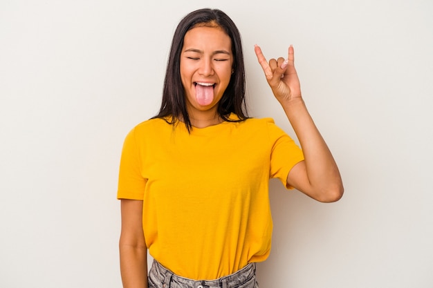 Joven mujer latina aislada sobre fondo blanco mostrando gesto de rock con los dedos