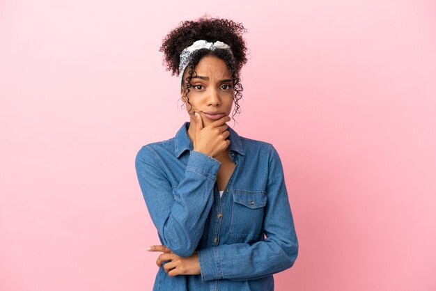 Joven mujer latina aislada sobre fondo rosa con dudas