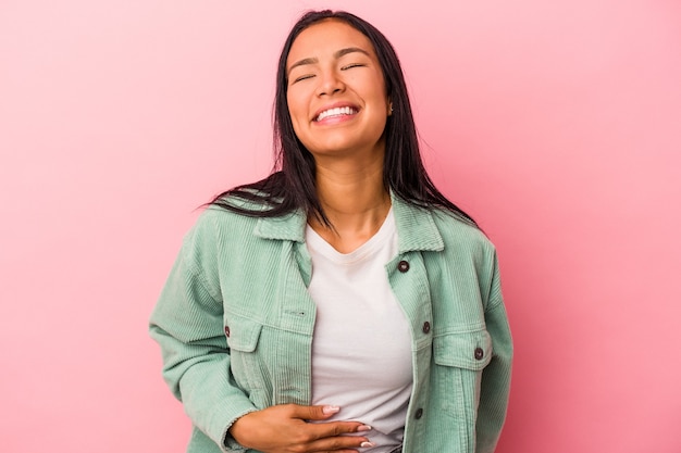 Joven mujer latina aislada sobre fondo rosa toca la barriga, sonríe suavemente, comiendo y concepto de satisfacción.