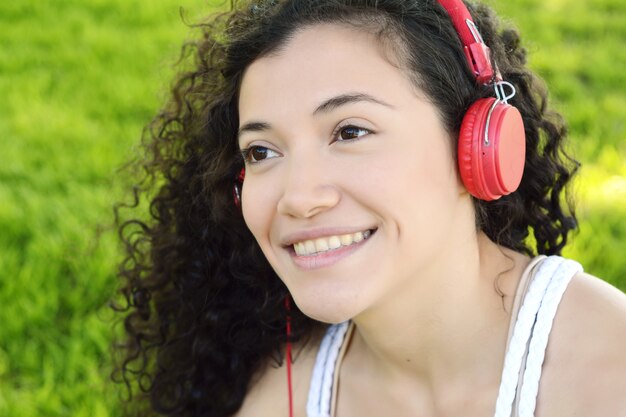 Joven mujer latina con auriculares en un parque.