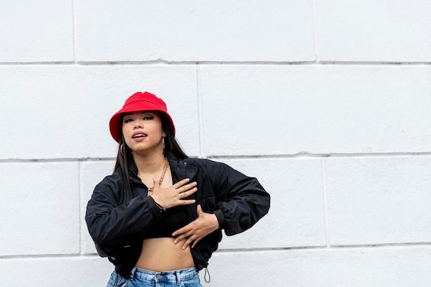 Joven mujer latina bailando hip hop en la calle con un sombrero rojo Panamá Centroamérica foto de archivo