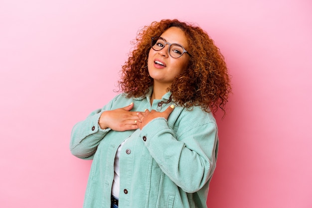 Foto joven mujer latina con curvas aislada en la pared rosa tiene una expresión amistosa, presionando la palma contra el pecho. concepto de amor.