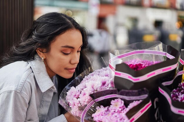 Joven mujer latina deleitándose con la fragante belleza de las coloridas flores en el puesto de un vendedor ambulante