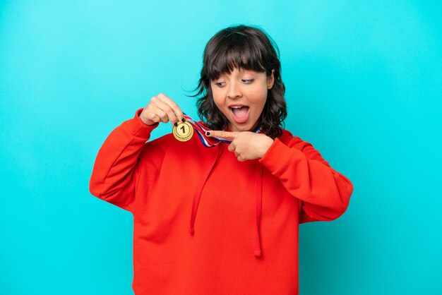 Joven mujer latina con medallas aislado sobre fondo azul.