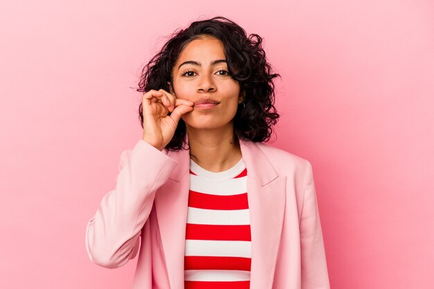 Joven mujer latina de moda aislada sobre fondo rosa con los dedos en los labios guardando un secreto.