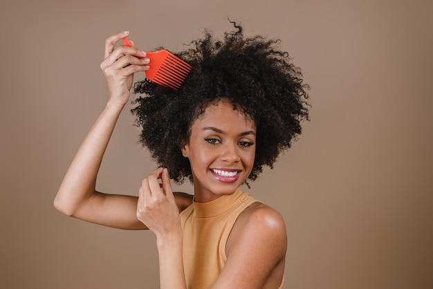 Joven mujer latina peinando el cabello Tenedor para peinar el cabello rizado Fondo pastel