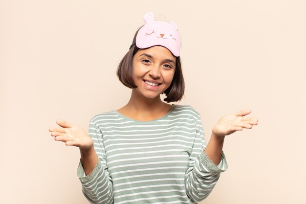 Joven mujer latina sonriendo alegremente dando un cálido, amable y cariñoso abrazo de bienvenida, sintiéndose feliz y adorable