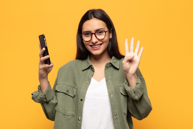 Joven mujer latina sonriendo y mirando amistosamente, mostrando el número cuatro o cuarto con la mano hacia adelante, contando hacia atrás