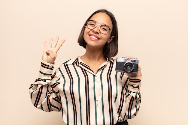 Joven mujer latina sonriendo y mirando amistosamente, mostrando el número cuatro o cuarto con la mano hacia adelante, contando hacia atrás